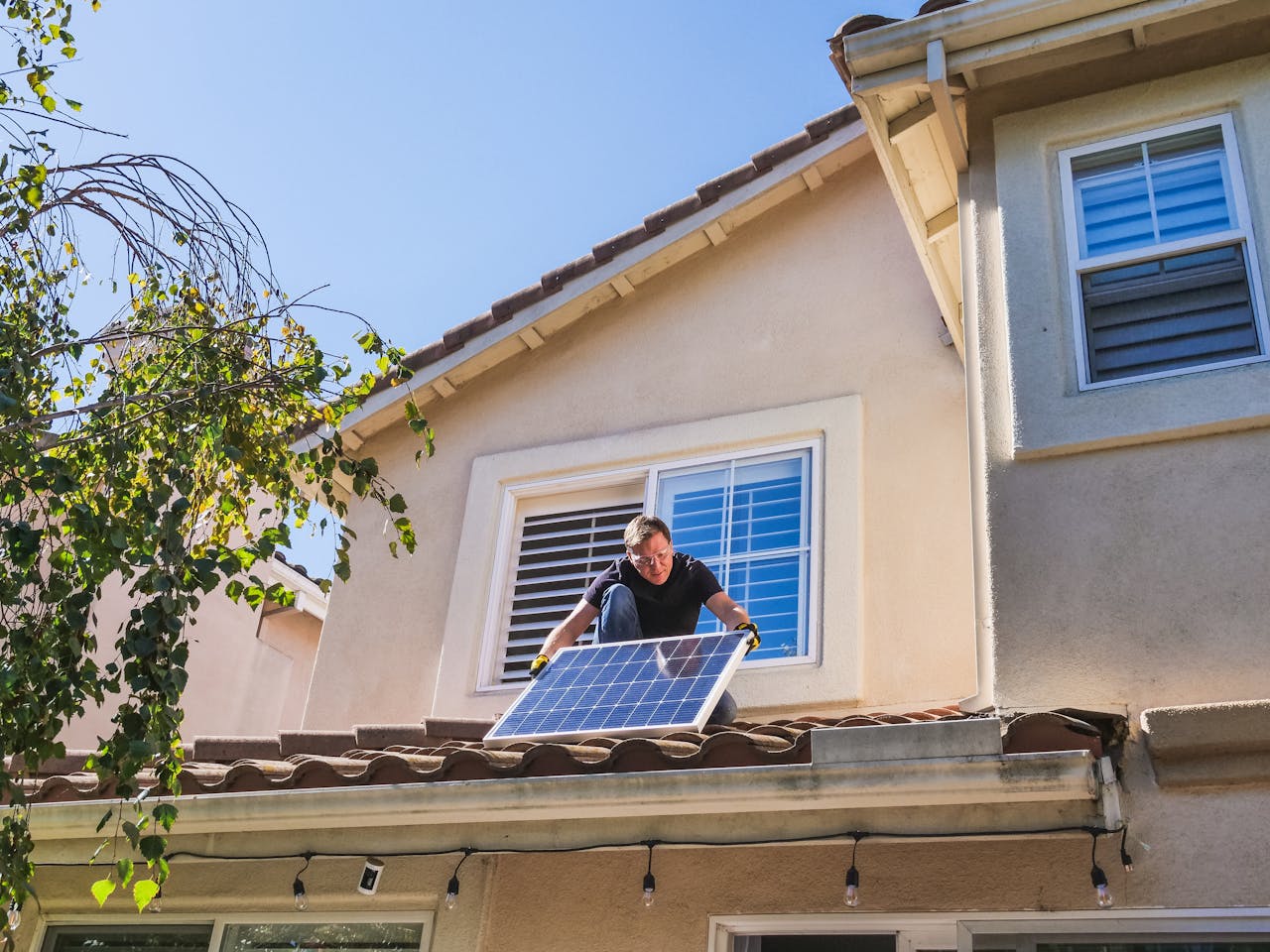 Sistema Solar Híbrido: Energía Solar con Mayor Flexibilidad Solar technician installing photovoltaic panels on a sunny rooftop.